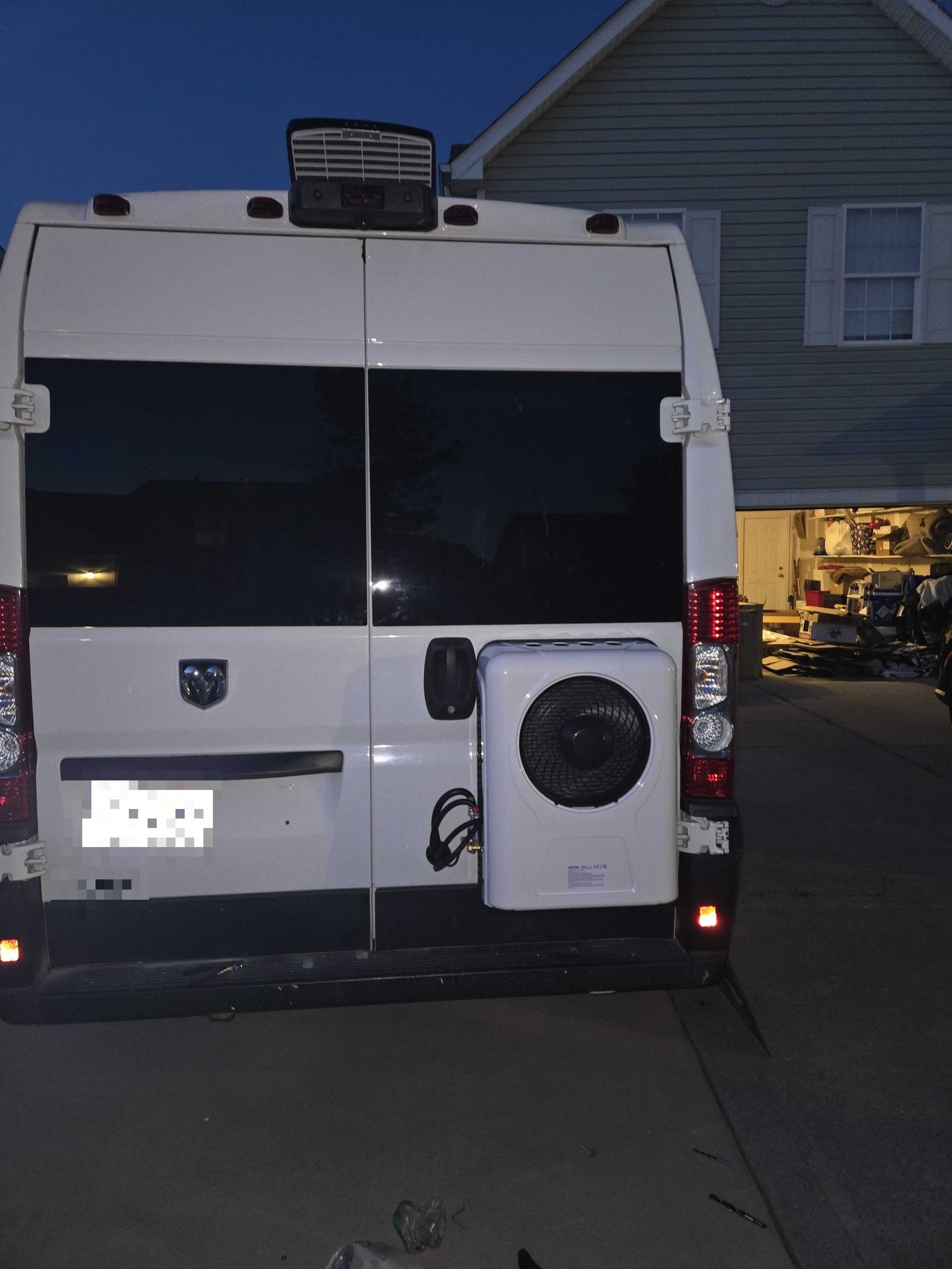 Vevor 12V mini split condenser unit mounted on the exterior of the right rear door of a white Ram ProMaster high roof van