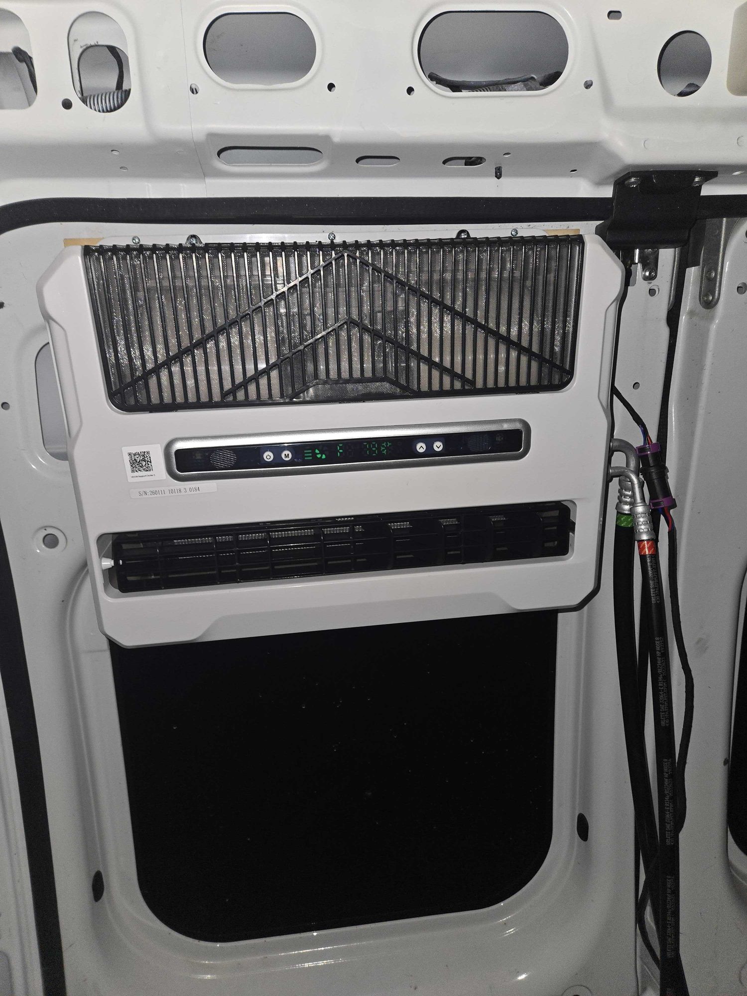 Vevor 12V mini split evaporator head mounted on the interior of the van's rear door, control panel reading 79 degrees Fahrenheit, R134a refrigerant lines routed to the right